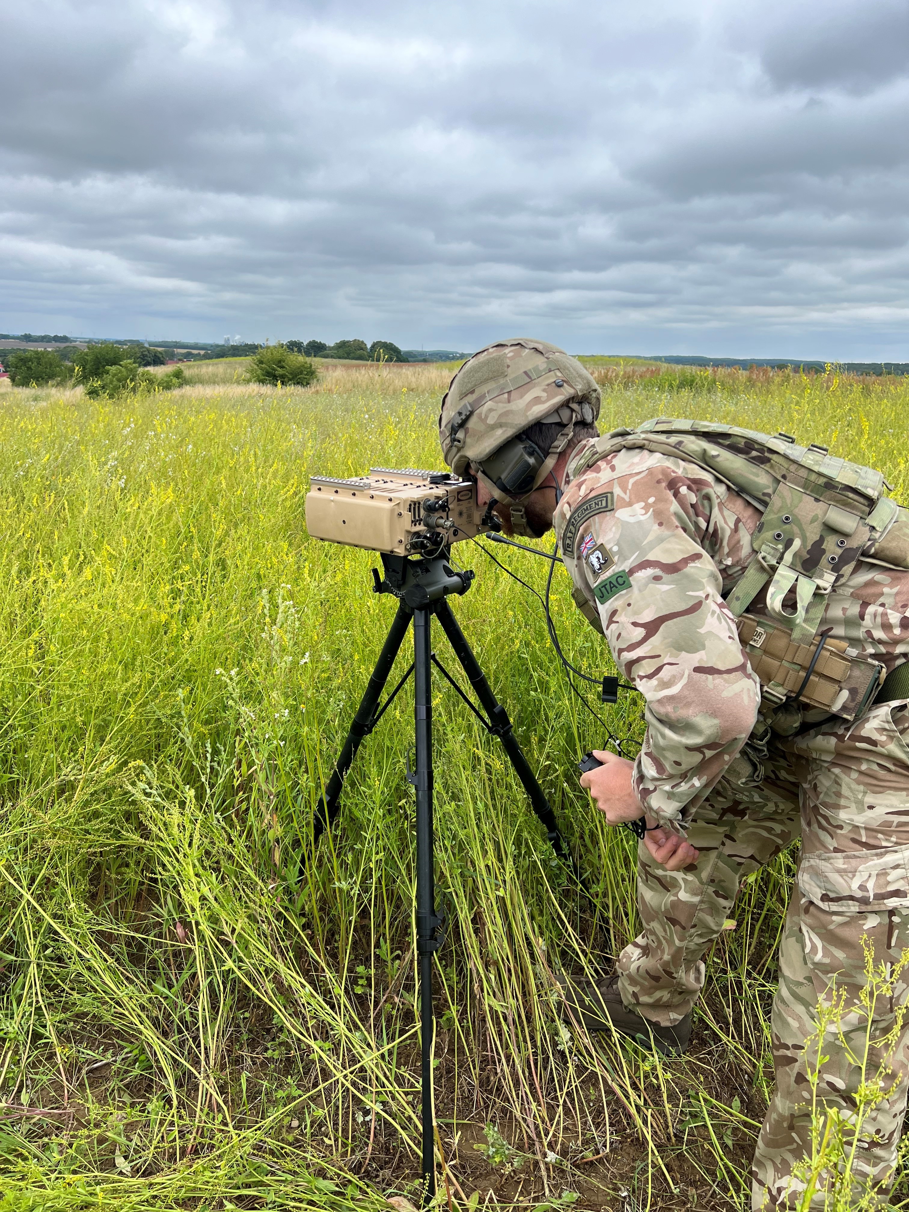 Image shows RAF Regiment using a ground-based laser designator.in grassy area.